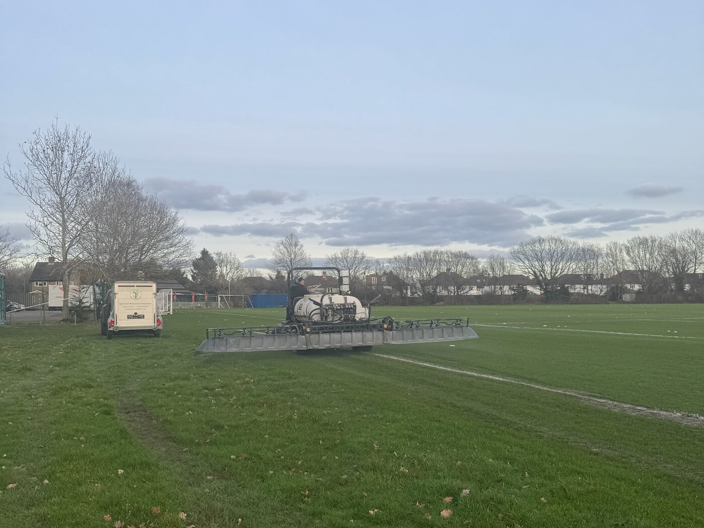 Tractor-mounted boom sprayer treating a sports pitch